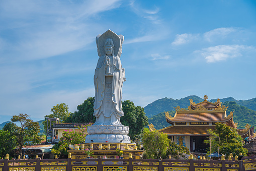 Majestic white Buddha statue on blue sky background. The Lady Buddha (the Bodhisattva of Mercy) at the Buu Lam Tu Pagoda which attracts tourists to visit spiritually on weekends in Vung Tau, Vietnam