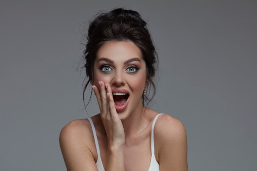Portrait of surprised young beautiful woman with hands on mouth.