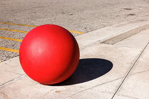 Decorative, concrete bollard    in the shape of a sphere in the street.