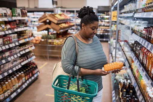 Portrait of black young woman choosing dairy products while grocery shopping in supermarket