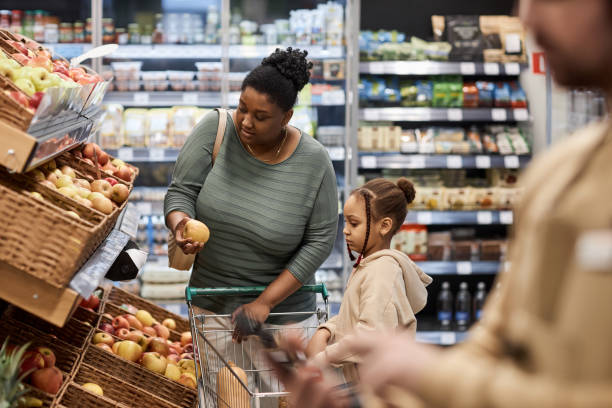 슈퍼마켓에서 식료품을 쇼핑하는 어린 소녀와 함께 있는 흑인 젊은 여성 - home economics class 뉴스 사진 이미지