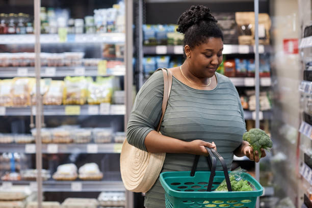 Real black woman buying fresh vegetables in supermarket