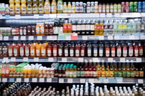 Background image of supermarket with shelves stacked with various drinks in row, copy space