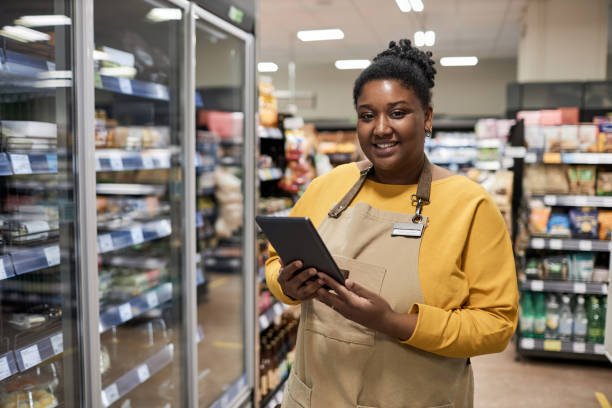 istock Smiling black woman enjoying work in supermarket and looking at camera 1480439914