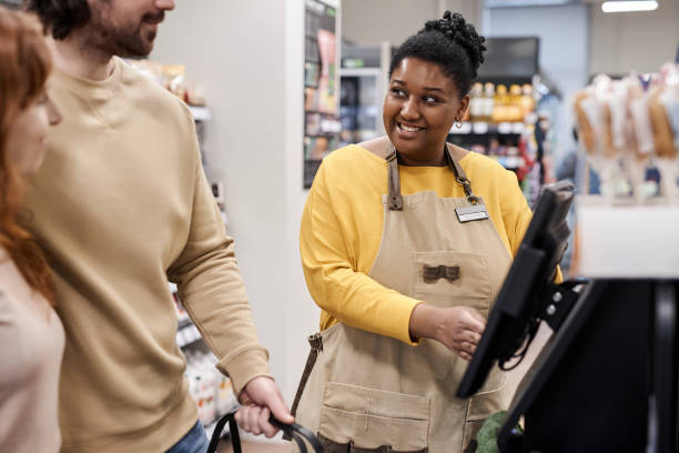 istock Young black woman helping customers with self checkout machine in supermarket 1480439917