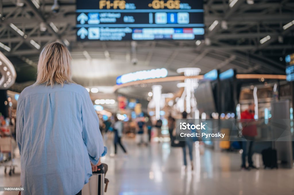 Solo Traveler Heading to a Flight Gate Rear view of a woman at the airport walking to her departure gate. Travel concept Airport Stock Photo