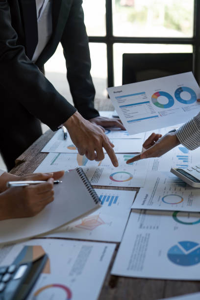 Diverse businesspeople cooperate work together discussing company financial statistics, multiracial colleagues employees collaborate brainstorm with finance document at meeting. close up shot