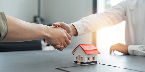 Agente inmobiliario y cliente estrechando la mano después de terminar contrato después de sobre seguro de hogar y préstamo de inversión photo