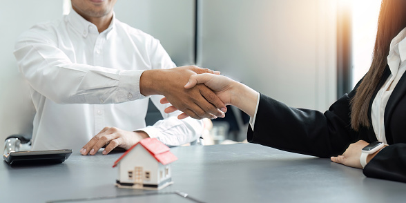 Agente inmobiliario y cliente estrechando la mano después de terminar contrato después de sobre seguro de hogar y préstamo de inversión photo