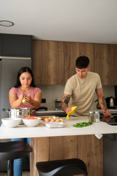istock Two young latin people cooking and cleaning kitchen counter at kitchen. 1480471820