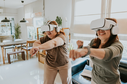 Two asian woman enjoy her weekend activity together with playing exercise game together, boxing game with virtual reality simulator.