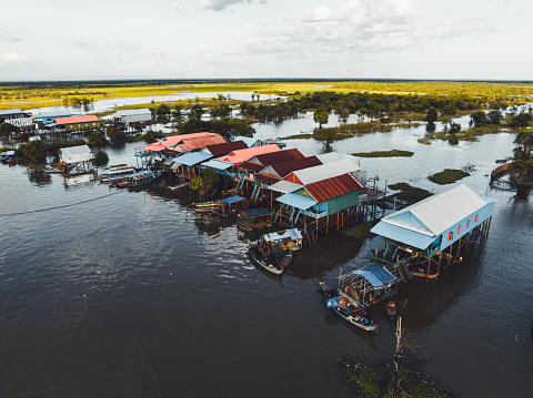 Stilt Houses in cambodian village of  Kampong Phluk Floating Village Aerial Drone Point of View. Stilt Houses, Fishing Boats and Fishing Farm Houses of Kampong Phluk - the well known Floating Village near Siem Reap and Lake Tonle Sap - situated close to the watered rural rice fields. Edited, Modified Colors and strong photo processing. Kampong Phluk Floating Village, Siem Reap Province, Prasat Bakong, Cambodia, South East Asia, Asia.