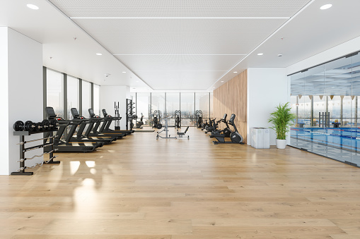 Modern Gym Interior With Swimming Pool, Treadmills, Exercise Bikes, Sports Equipments And City View Through Window