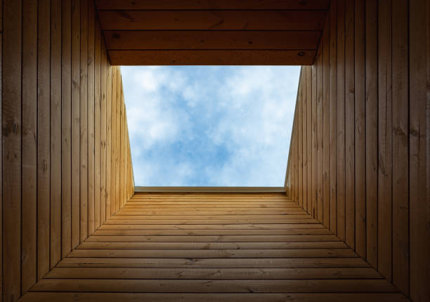 istock Dormer window in a wooden sloping ceiling overlooking blue sky. Sunlight enters the room through a window. Mansard roof 1480491507