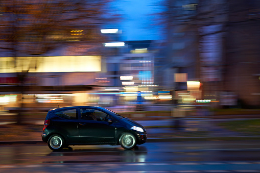 Stuttgart, Germany - February 03. 2023: Car on slippery road at night in motion. Vehicle in the rainy city. Panning shot.