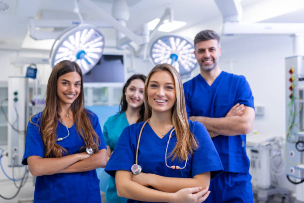 istock Closeup front view of group of mixed age doctors and nurses standing side by side and looking at the camera. Young female doctor is in the front. 1480492377