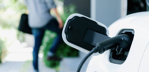 istock Focus EV charging station at home with blur progressive man in background. 1480495483