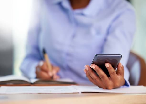 istock Hands, phone or writing in notebook for financial data, company budget or insurance accounting in business office. Zoom, black woman or mobile technology for finance worker, tax schedule or fintech 1480495514