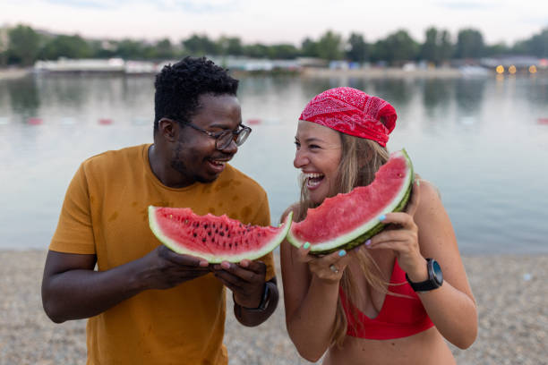 istock A young multiracial couple near a river is eating watermelons. 1480500430