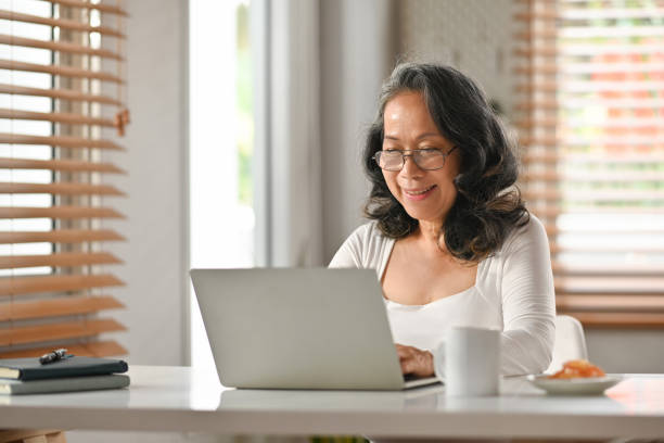 istock Grey haired senior woman in glasses working remotely from home office with laptop computer. 1480503032
