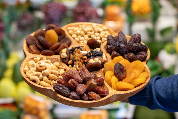 istock Mixed nuts platter. Wood nut plate prepared with hazelnuts, cashews, dates, apricots and grapes. 1480503656