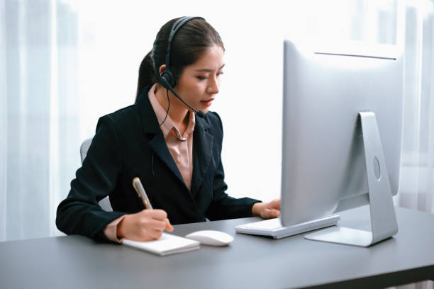 istock Enthusiastic asian call center with headset and microphone working on her laptop 1480503736
