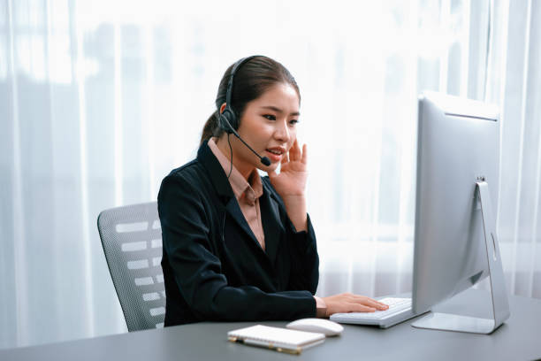 istock Enthusiastic asian call center with headset and microphone working on her laptop 1480503829