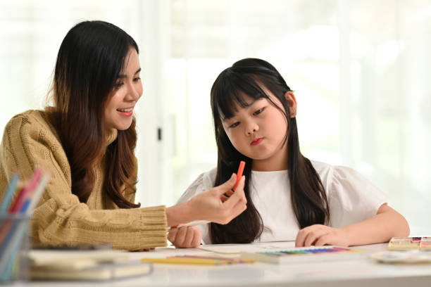 istock Young mother helping her daughter doing creative art homework at home. Homeschooling, learning and family concept. 1480505277