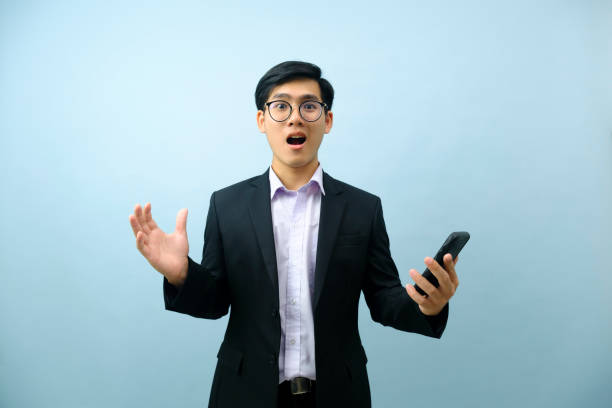 Portrait of surprised businessman holding mobile phone. stock photo