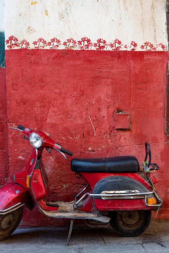 Cute red motor scooter parked against a red painted wall in the Islamic quarter of Cairo near the  Khan el Khalili Bazaar, Egypt.