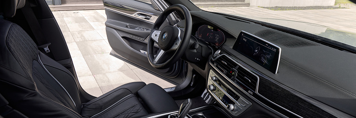 BMW 740D interior with open driver's door. The interior is finished with wood and black leather. Katowice, Poland - 13.06.2021