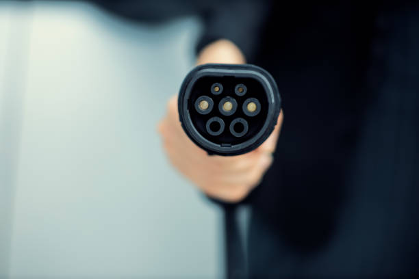 istock Focus closeup hand pointing EV plug for electric vehicle as progressive idea. 1480510654