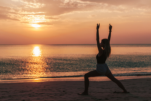 Caucasian fitness woman practicing yoga at sunset