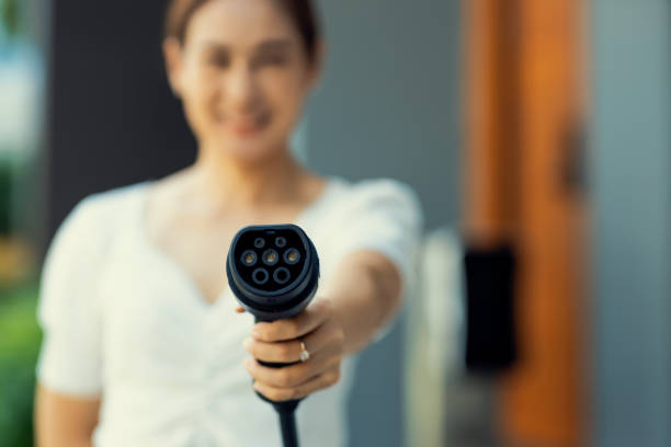istock Focus hand pointing EV charger plug at camera with progressive blur background. 1480512548
