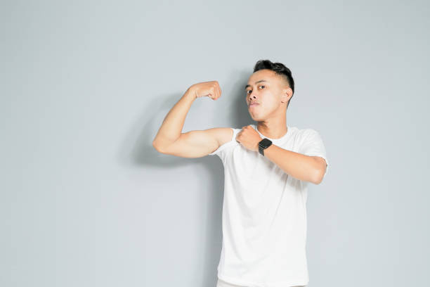 a young man is showing a strong gesture, isolated on a gray background