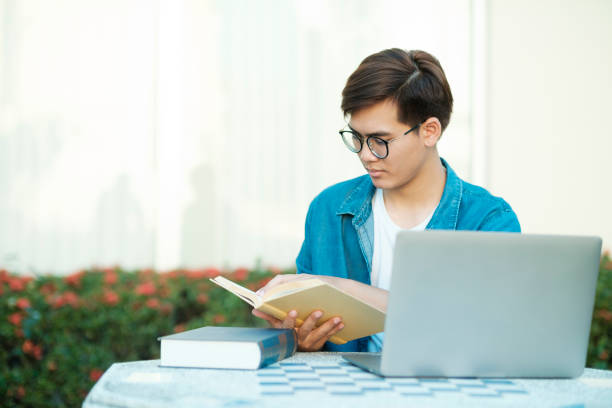 estudiante que estudia al aire libre usando una computadora portátil. - outdoors book reading accessibility fotografías e imágenes de stock