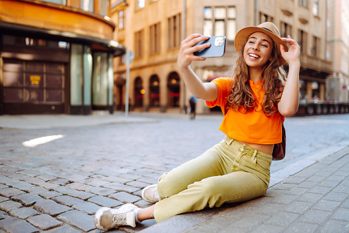 Happy woman holding mobile phone takes selfie using smartphone camera.