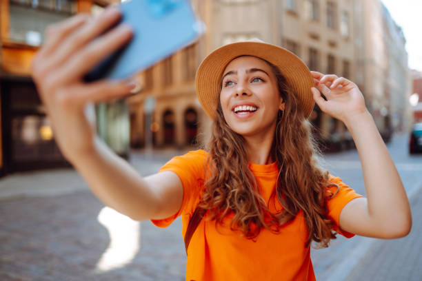 istock Happy woman holding mobile phone takes selfie using smartphone camera. 1480514961
