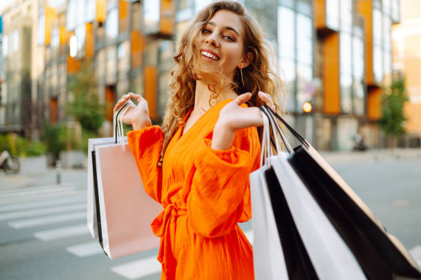 Happy woman with shopping bags walking on a sunny street. Happy woman with shopping bags walking on a sunny street. The concept of lifestyle, buying, selling, consumerism. young women shopping stock pictures, royalty-free photos & images