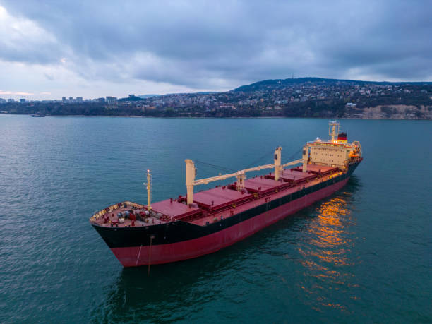 aerial view of a bulk carrier at evening showcases a stunning display of lights reflecting off the water as the massive vessel cuts through the waves. stock photo
