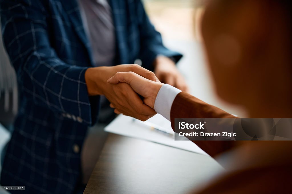 Close up of business people shaking hands in the office. Close up of coworkers handshaking while greeting during business meeting in the office. Handshake Stock Photo