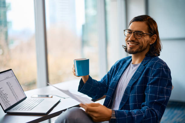 istock Happy entrepreneur having a cup of coffee while working in the office. 1480538563