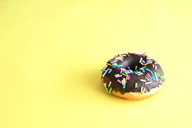istock A donut with sprinkles is on a yellow background isolated, copy space 1480539123