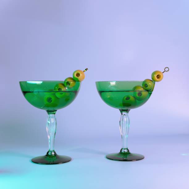 洗練された一口:装飾的なアールデコグラスにオリーブと2つのマティーニ - martini martini glass dirty martini olive ストックフォトと画像