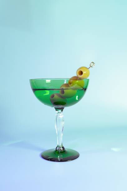 ヴィンテージグリーングラスにオリーブとエレ�ガントなアールデコダーティマティーニ - martini martini glass dirty martini olive ストックフォトと画像