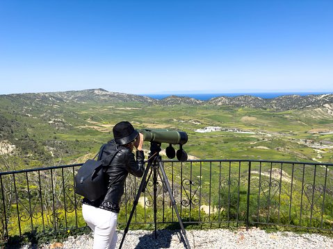 Woman looking through a telescope at the Cyprus landscape and Türkiye