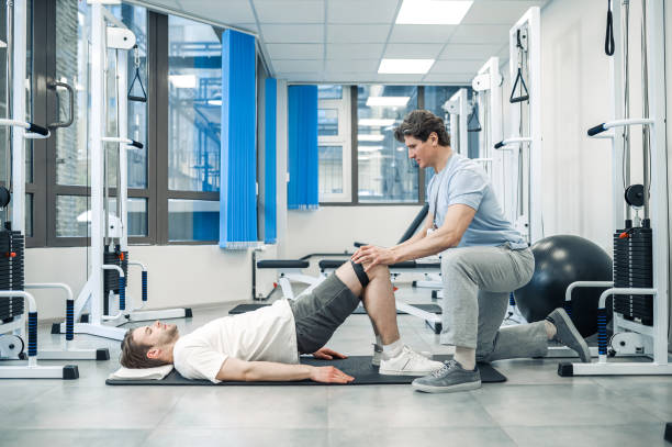 istock Experienced instructor assisting a man in a rehabilitation workout 1480545237