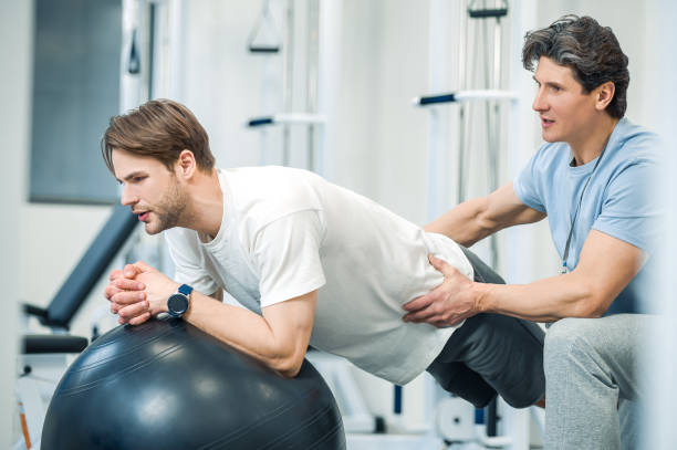 istock Man having exersicing on fitball with instructor 1480545254