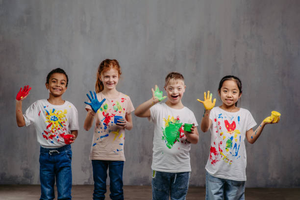 Portrait of happy kids with finger colours and painted t-shirts, studio shoot. stock photo