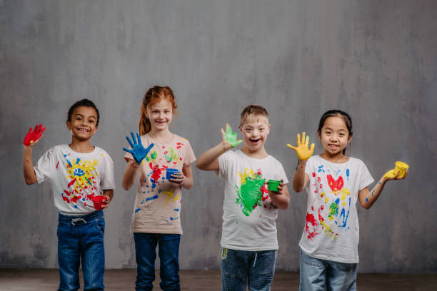 Portrait of happy kids with finger colours and painted t-shirts, studio shoot. Portrait of happy kids with finger colours and painted t-shirts. special needs child pictures stock pictures, royalty-free photos & images
